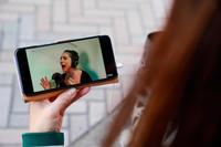 レディー・ガガのパフォーマンスをスマートフォンで視聴する女性＝東京都（ゲッティ＝共同）