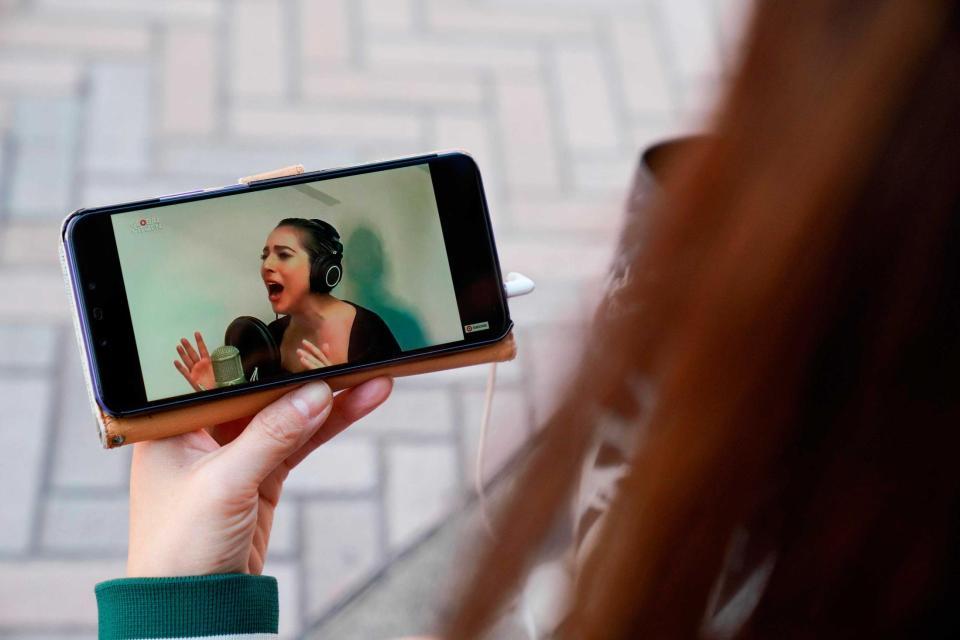 レディー・ガガのパフォーマンスをスマートフォンで視聴する女性＝東京都（ゲッティ＝共同）