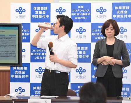 会見中、喉を潤す大阪府・吉村洋文知事（左）＝１４日夜、大阪府庁（撮影・高部洋祐）