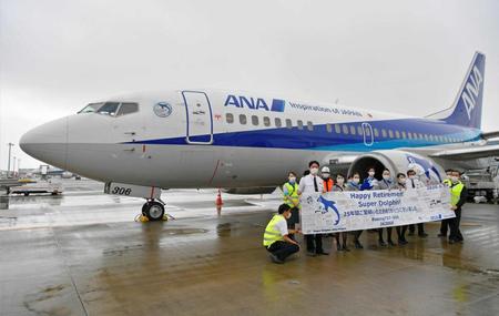 　ラストフライトを終え、羽田空港に到着した全日空ボーイング７３７－５００「スーパードルフィン」の前で記念撮影する客室乗務員ら