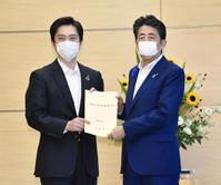 　安倍首相（右）に新型コロナウイルス対策に関する要望書を提出する大阪府の吉村洋文知事＝１４日午後、首相官邸