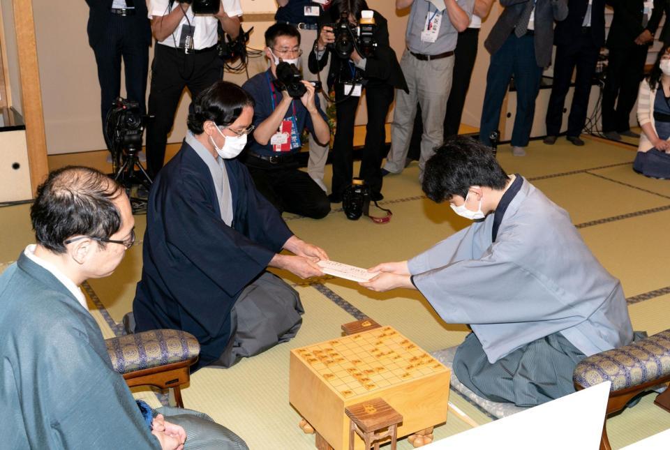 　立会人に封じ手を渡す藤井聡太七段（右・左は木村王位）＝日本将棋連盟提供