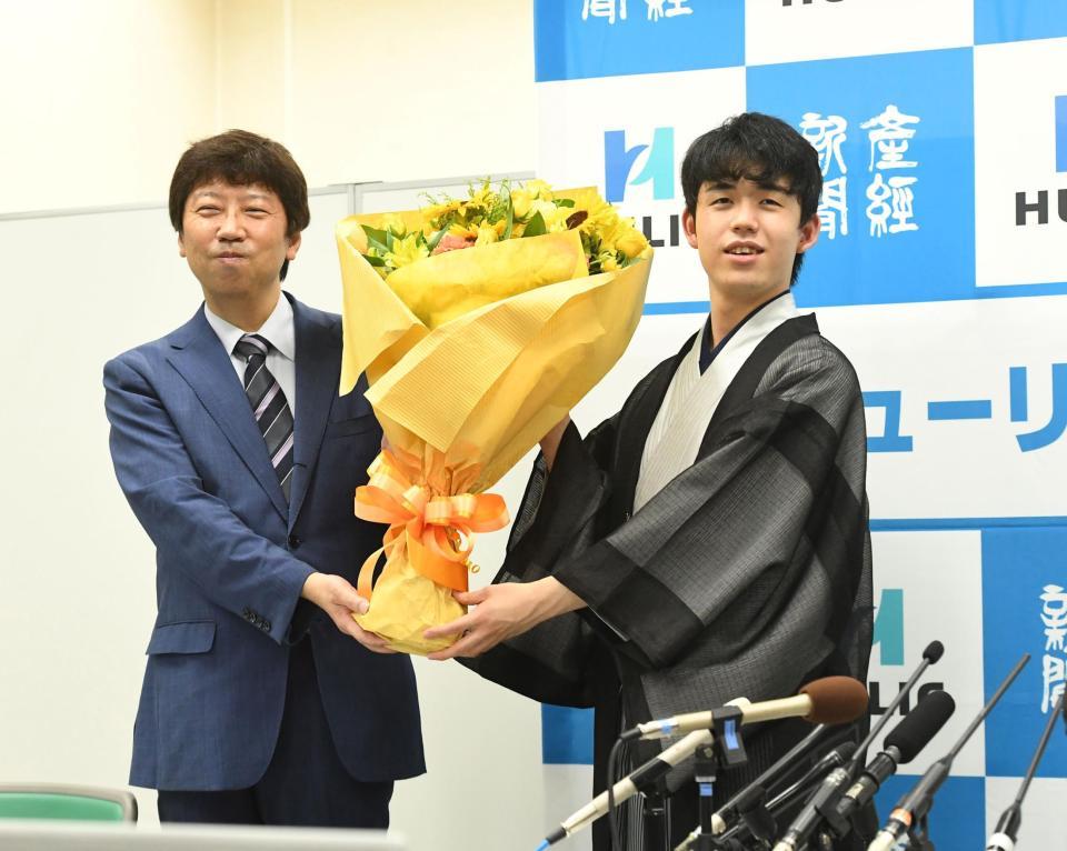 史上最年少でタイトルを獲得し、師匠の杉本昌隆八段（左）から渡された花束を手にする藤井聡太棋聖＝関西将棋会館（撮影・北村雅宏）