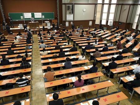 緊急事態宣言下で、初の実施となる大学入学共通テストに臨む受験生。座ってはいけない席上にテープで「×」マークが貼られていた＝東京都文京区の東大