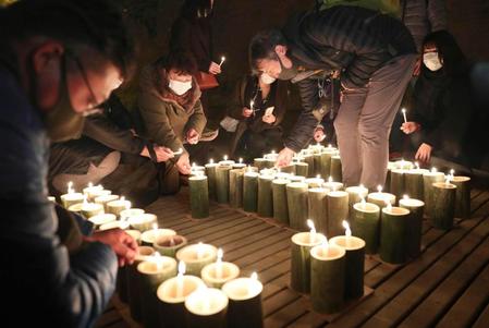 　犠牲者を追悼するため灯籠に火をともす人たち＝神戸市兵庫区の湊川隧道