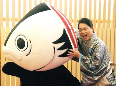 　高知のご当地キャラ・カツオ人間にかぶりつく三山ひろし＝大阪市・新歌舞伎座