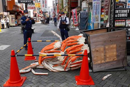 　壊されたカニ料理店前のオブジェを調べる警察官＝５日、大阪・ミナミ
