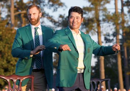 米ゴルフのマスターズ・トーナメントで、日本男子初のメジャー制覇を果たし、グリーンジャケットに袖を通す松山英樹。左は前年優勝のダスティン・ジョンソン＝11日、米ジョージア州のオーガスタ・ナショナルＧＣ（ロイター＝共同）