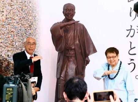 　志村けんさんの銅像の前で「アイーン」のポーズをとる兄知之さん（左）と高木ブー＝東京都東村山市　