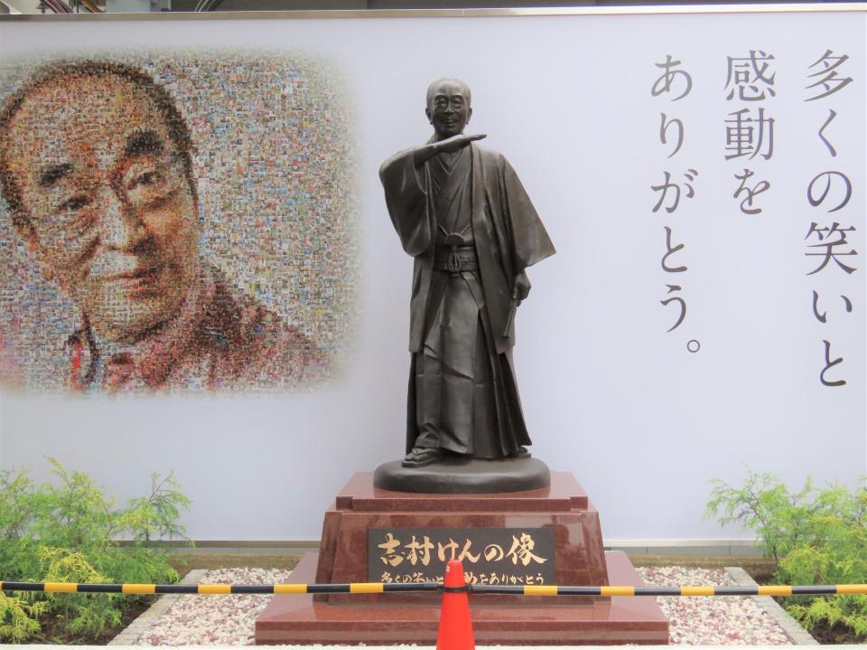 　志村けんさんの銅像をスマホで撮影する多くの市民＝東京・東村山駅前
