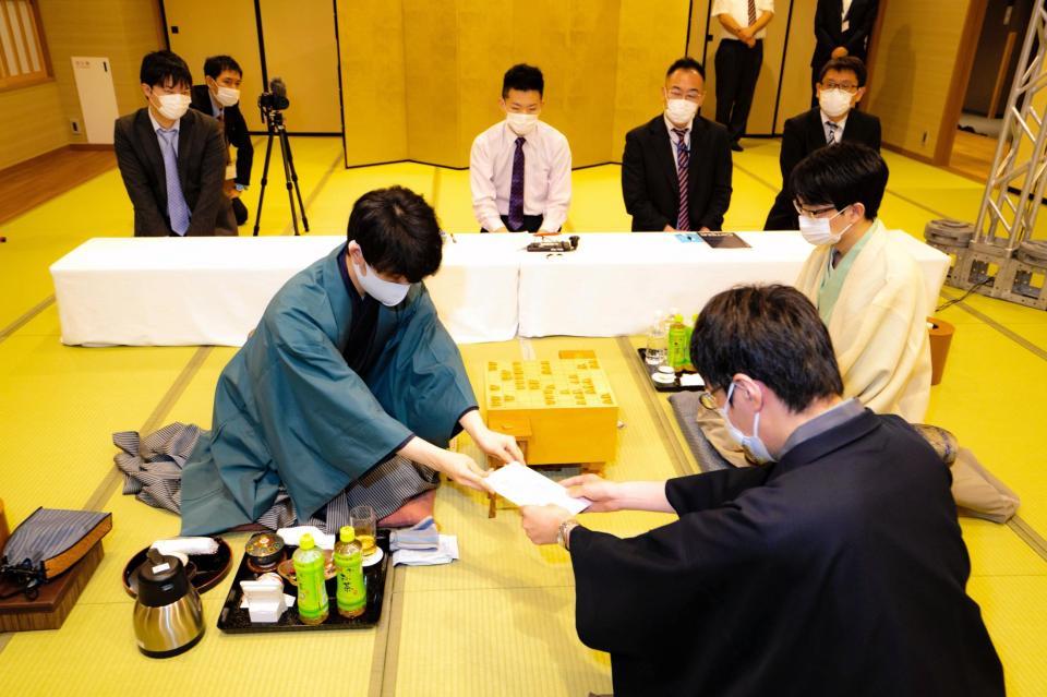 封じ手を立会人の広瀬章人八段（手前）に手渡す藤井聡太王位（提供：日本将棋連盟）