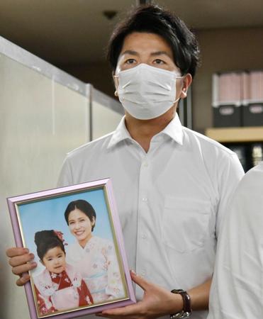 　記者会見を終え、妻真菜さんと長女莉子ちゃんの写真を手にする松永拓也さん＝東京・霞が関の司法記者クラブ