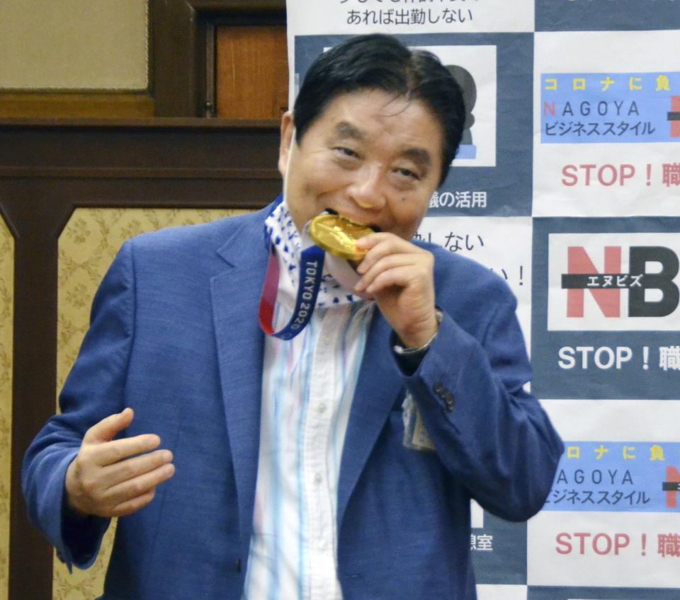 金メダルをかじる河村たかし名古屋市長＝４日（提供・共同通信社）