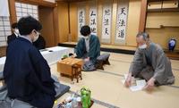 立会人の中田功八段（右）が封じ手を示し、対局を再開する藤井聡太王位（中央）と豊島将之竜王（代表撮影）