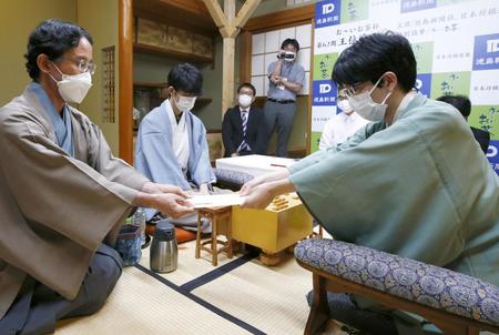 立会人に（左端）に封じ手を渡す豊島将之竜王（右）。左から２人目は藤井聡太王位（代表撮影）