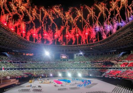 開会式に登場したパラリンピックのシンボルマーク「スリーアギトス」（下）と打ち上げられる花火＝24日夜、国立競技場