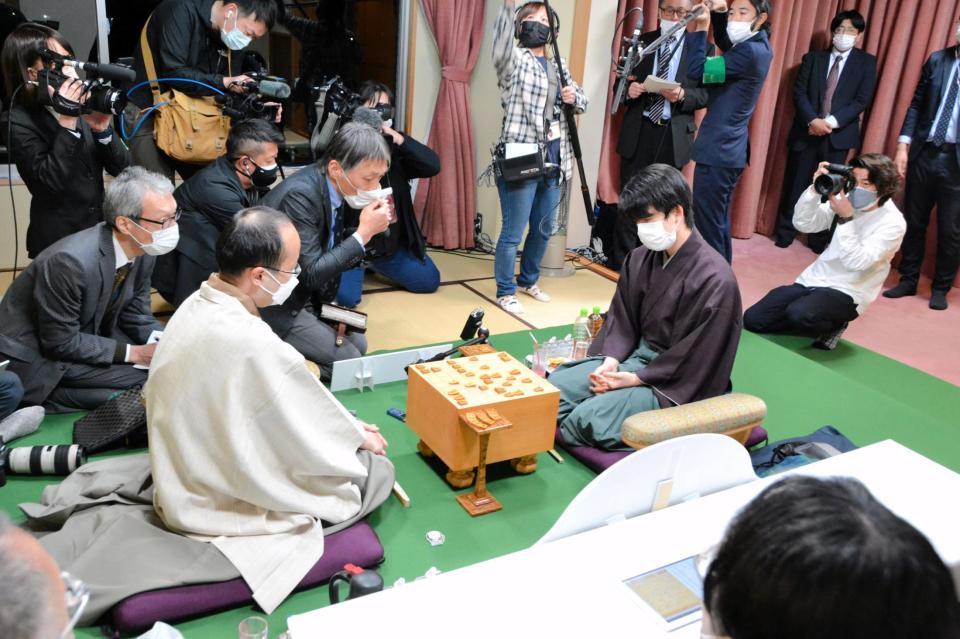 渡辺王将（左手前）に勝利した藤井竜王（右）。終局後、大勢の報道陣に囲まれる＝日本将棋連盟提供