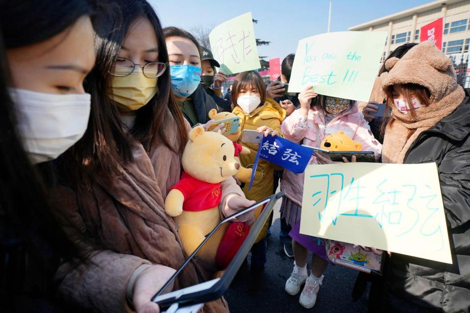 会場前で「くまのプーさん」の縫いぐるみを手にスマホで実況中継を見る羽生ファン（共同）