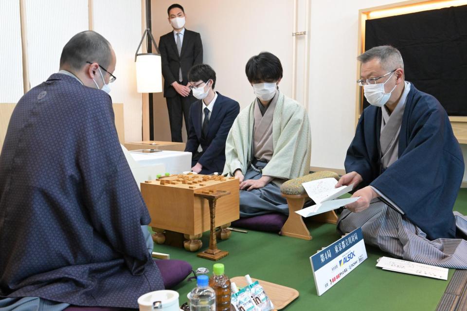 　第７１期ＡＬＳＯＫ杯王将戦七番勝負第４局２日目。立会の中村修九段（右端）が示した封じ手を見る渡辺明王将（左）と藤井聡太竜王（右から２人目）＝代表撮影