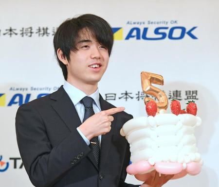 　王将戦を制し一夜明け会見で５冠を表す風船ケーキを持って笑顔の藤井聡太新王将＝パレスホテル立川（撮影・三好信也）