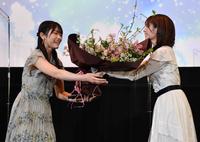 竹達彩奈（右）から花束を渡されて笑顔を見せる日向坂４６の丹生明里＝東京・新宿バルト９（撮影・西岡正）
