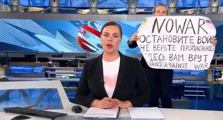 　ロシアのテレビの生放送中、キャスターの背後で「戦争をやめて」などと書いた紙を掲げる女性（ウクライナのポドリャク大統領府長官顧問のツイッターより、共同）