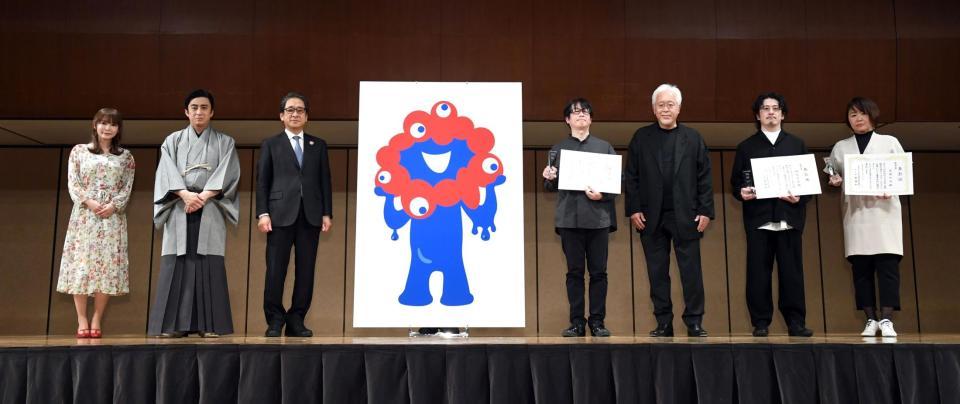 　最優秀作品「候補Ｃ」を中央に記念撮影する（左から）中川翔子、松本幸四郎、石毛事務総長、最優秀作品作者・山下浩平氏、原研哉座長、優秀作品作者・橋本浩彰氏、同・吉崎るみ氏（撮影・佐藤厚）