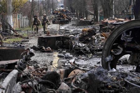　ウクライナの首都キーウ近郊ブチャで、破壊されたロシア軍戦車の近くを歩く兵士（ＡＰ＝共同）