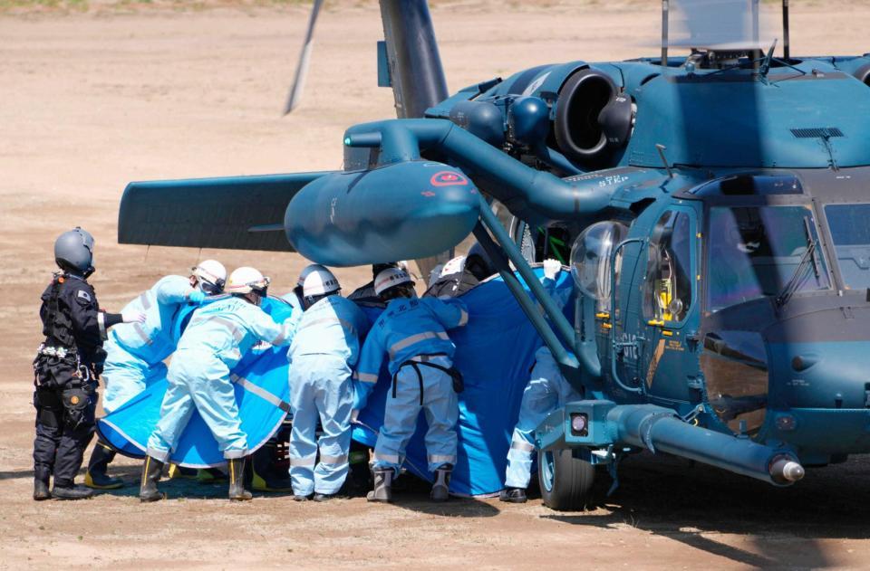 　自衛隊のヘリから救助された人を搬送する救急隊員ら＝北海道斜里町
