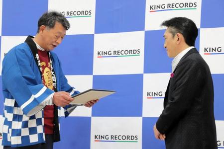野崎尚文大間町長（左）から委嘱状を渡される福田こうへい＝東京・江戸川橋のキングレコード