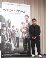 　大型ポスターの横でポーズをとる是枝裕和監督（撮影・園田高夫）