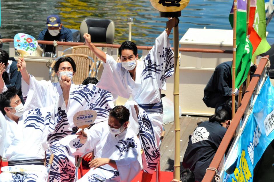　３年ぶりに開催された恒例の「船乗り込み」で船上から挨拶する際にグリコのポーズを見せる中村虎之助（後列右）ら＝大阪・道頓堀