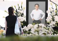 　通夜が営まれる増上寺に設置された献花台で安倍元首相の遺影を見つめる人（撮影・園田高夫）