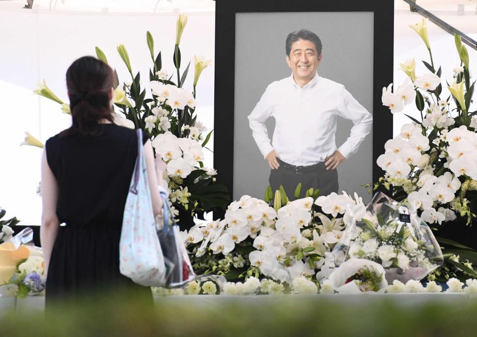 　通夜が営まれる増上寺に設置された献花台で安倍元首相の遺影を見つめる人（撮影・園田高夫）