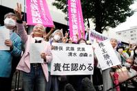 　判決後、東京地裁前で「株主勝利」などと書かれた紙を掲げ喜ぶ原告側弁護士や関係者