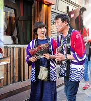 　妻・佳子さん（左）とチラシを配った赤井英和＝大阪・道頓堀