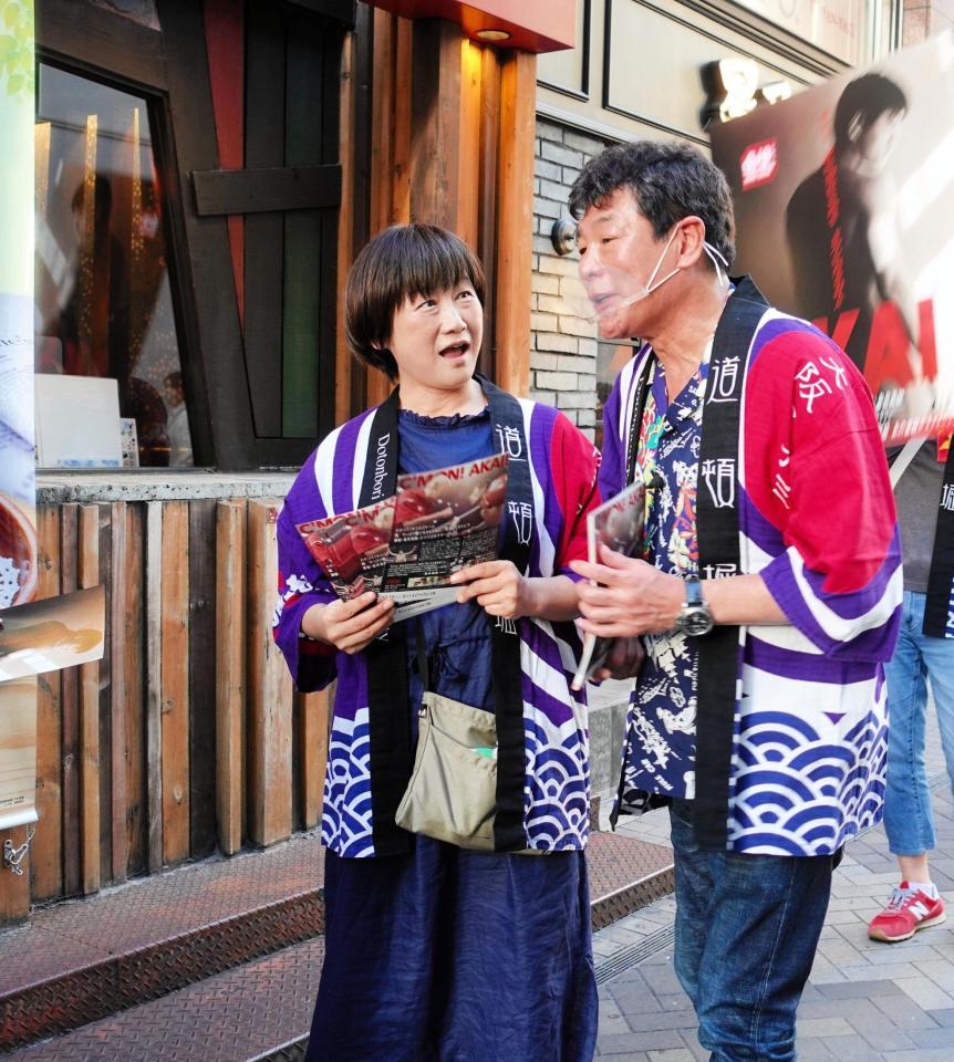 　妻・佳子さん（左）とチラシを配った赤井英和＝大阪・道頓堀