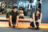 　腹筋ローラーに挑む原田龍二（左）と愛