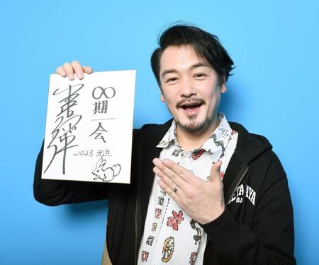 　「∞期一会」と記した色紙を掲げる小田井涼平（撮影・園田高夫）