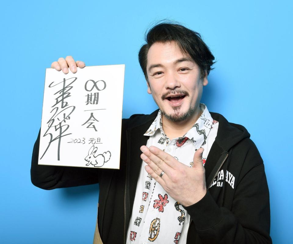 　「∞期一会」と記した色紙を掲げる小田井涼平（撮影・園田高夫）