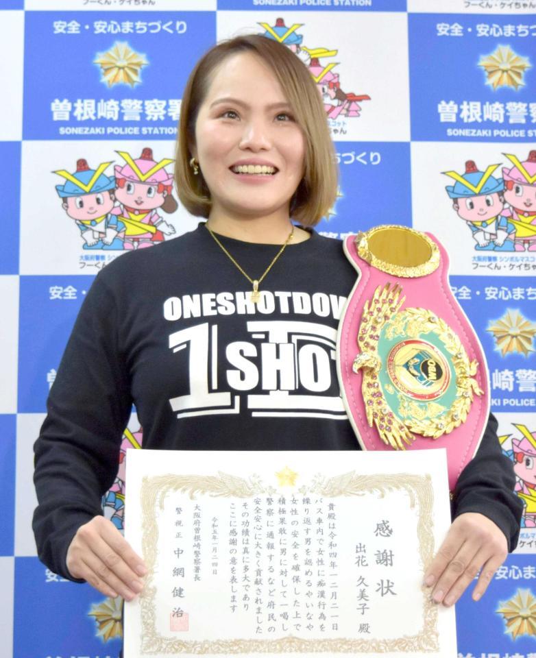 　チャンピオンベルトを肩にかけ、記念写真に納まる元プロボクサーの出花久美子さん＝２４日、大阪・曽根崎署