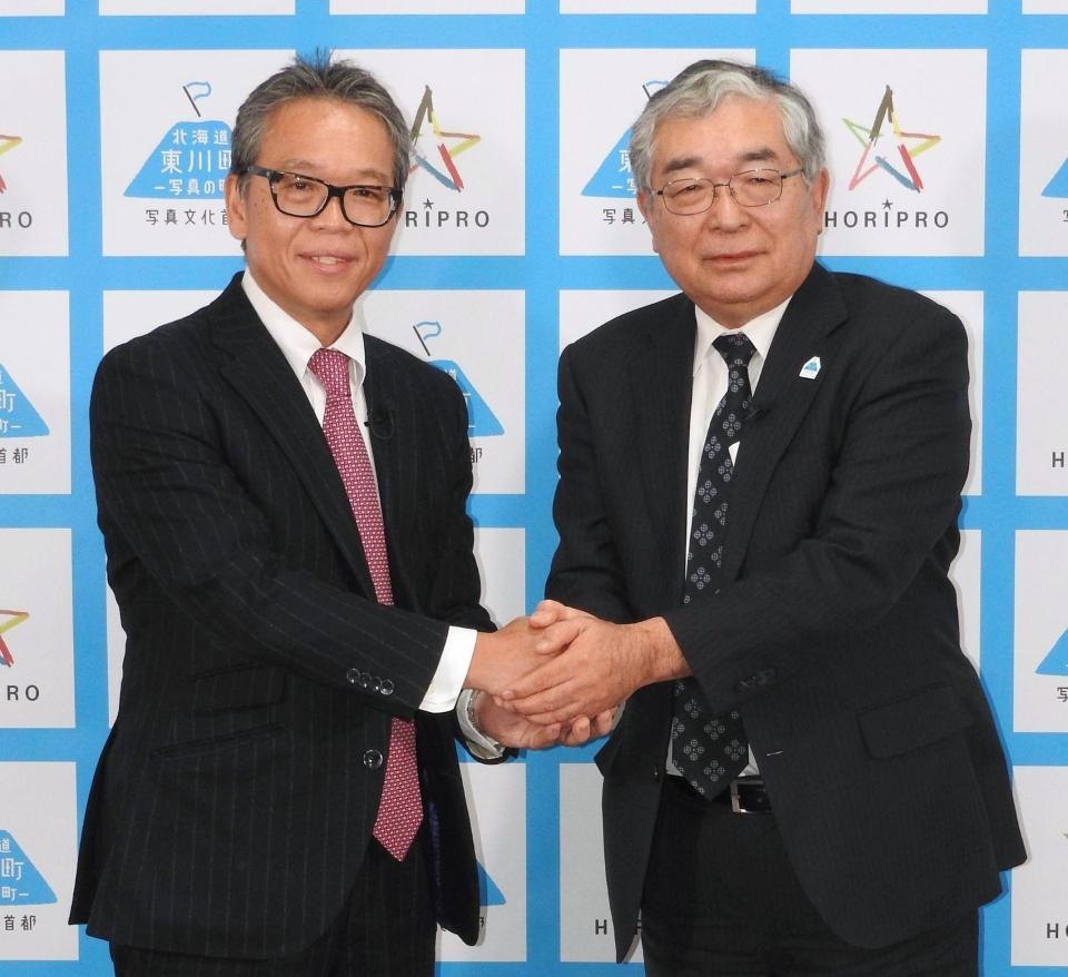　握手を交わすホリプロの菅井敦社長（左）と北海道東川町の松岡市郎町長