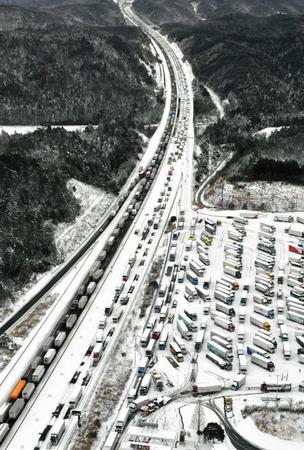 　大雪の影響でトラックなど多くの車が立ち往生する新名神高速道路。手前右は土山サービスエリア（共同通信社ヘリから）