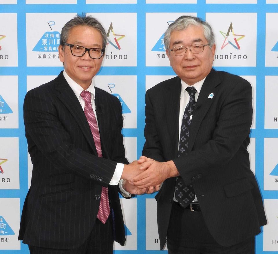 　握手を交わすホリプロの菅井敦社長（左）と北海道東川町の松岡市郎町長