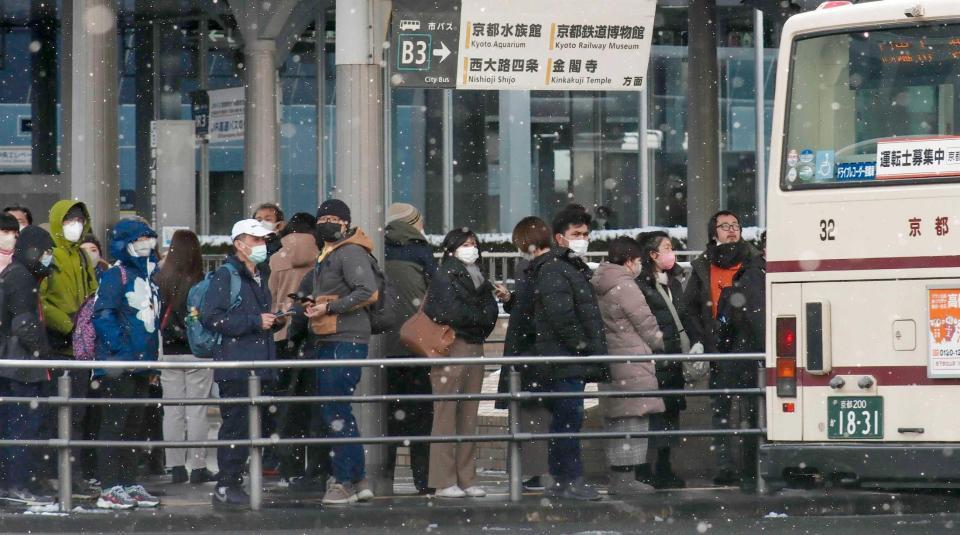 　雪が舞う中、ＪＲ京都駅前でバスを待つ人たち