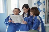 新聞記事を見る舞たち。左から、西口（マエダユミ）、舞（福原遥）、山田（大浦千佳）