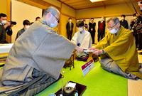 　封じ手を立会人に渡す渡辺明名人。中央は藤井聡太竜王（日本将棋連盟提供）