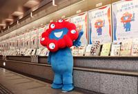 　張り出されたポスターを披露する「ミャクミャク」