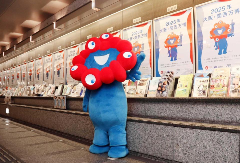 　張り出されたポスターを披露する「ミャクミャク」