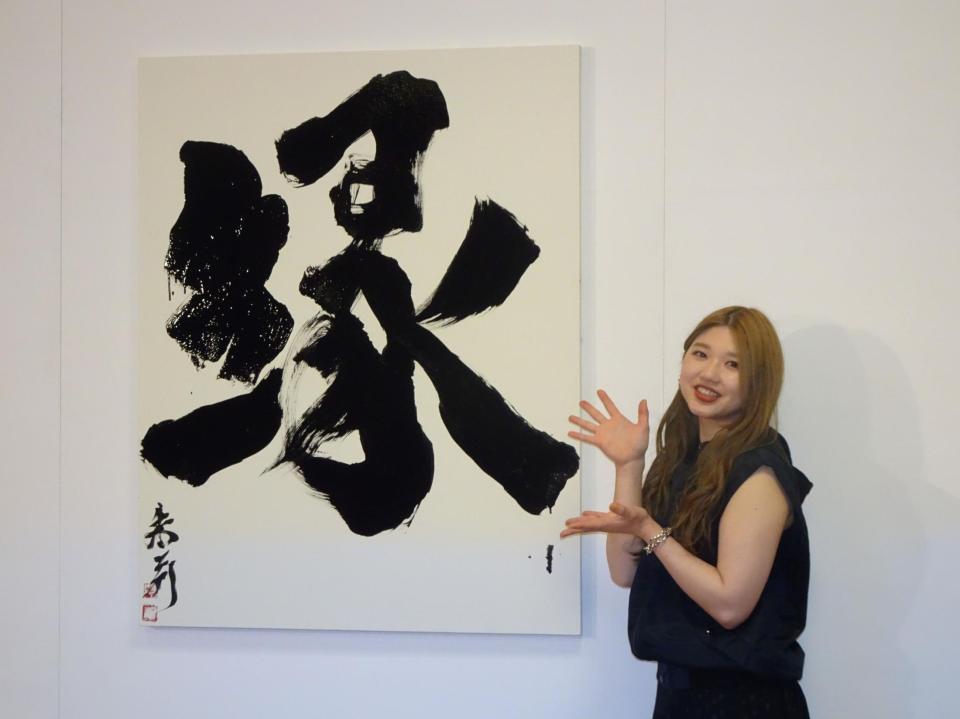 　自筆の書を前に笑顔を見せる竹内朱莉